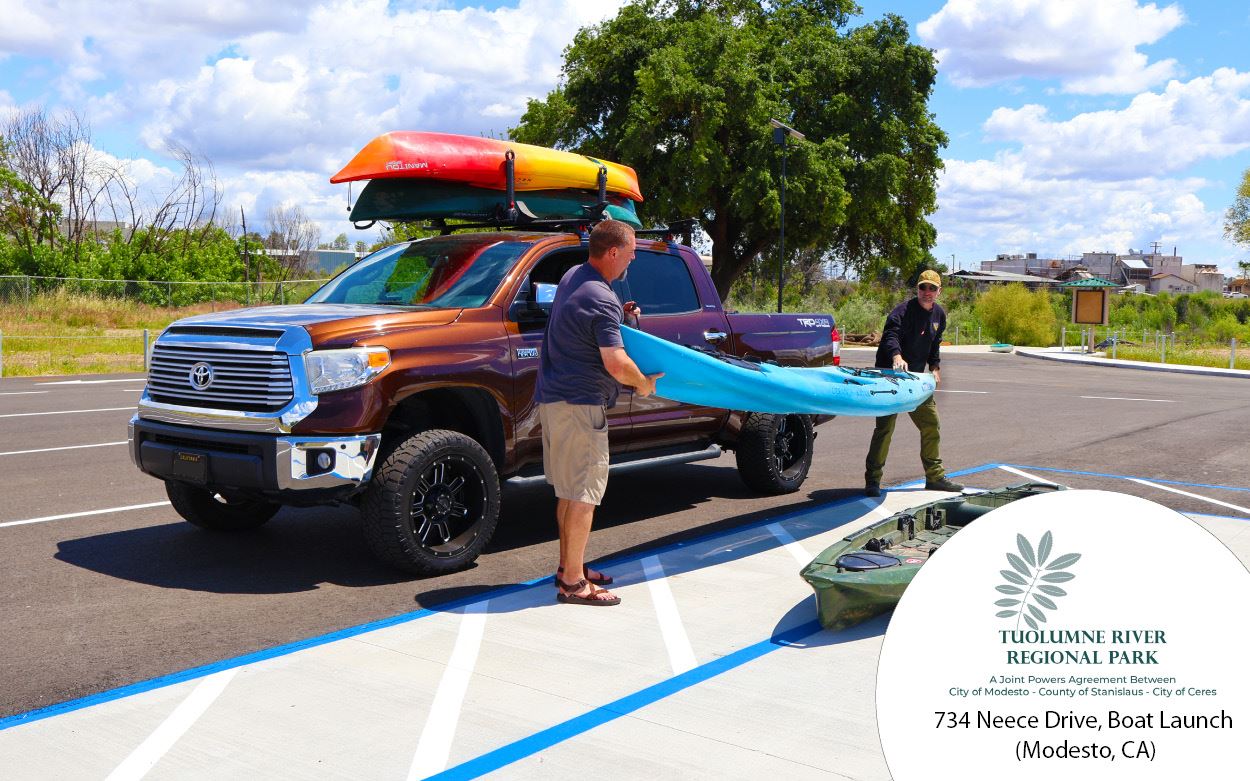 Image of two men unloading a river kayak off of a truck. 