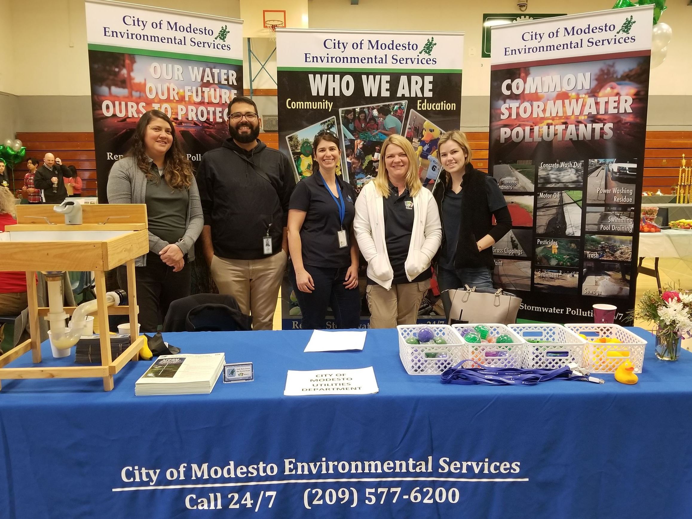 Five Environmental Services employees stand smiling at an indoor informational booth